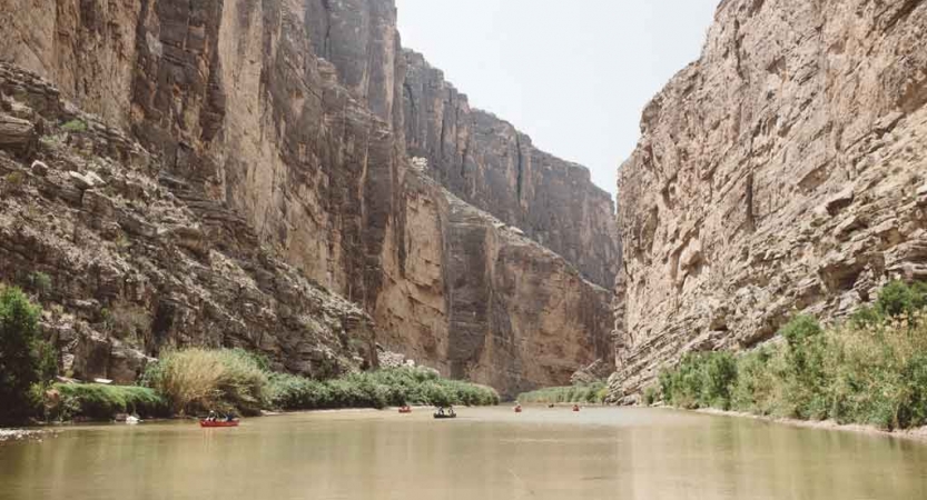 canoes are paddled on calm water between very high canyon walls on an outward bound gap year semester